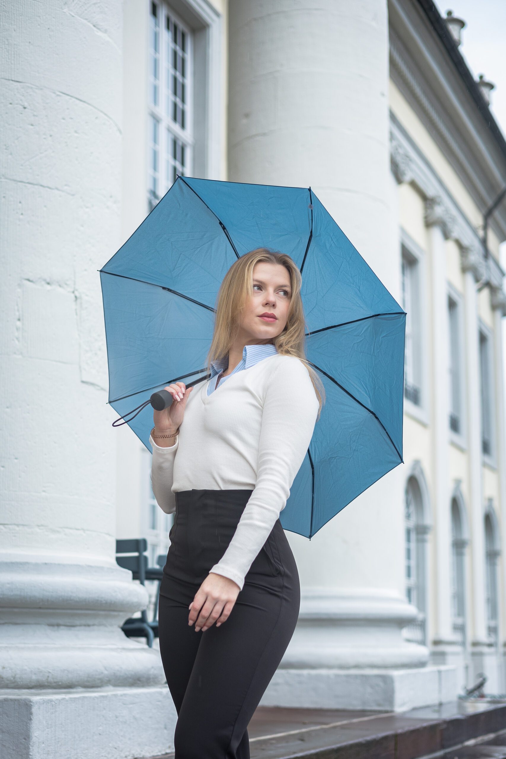 Eine Frau mit weißem Oberteil und blauem Regenschirm